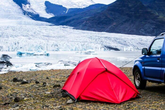 Red tent camping with car in Iceland
