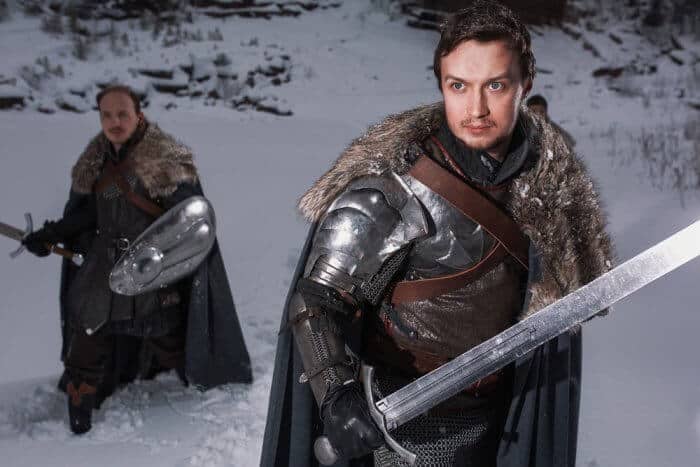 Two man holding swords in a wintery scene dress in medieval clothes for a film