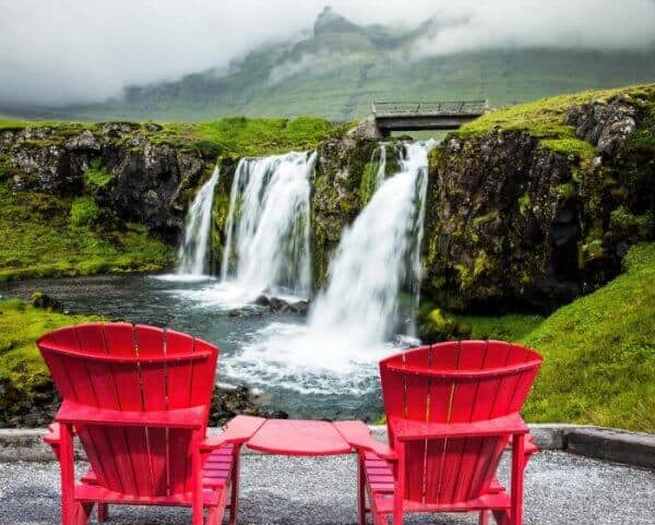 Two red wooden chairs overlooking a beautiful icelanddic waterfalll