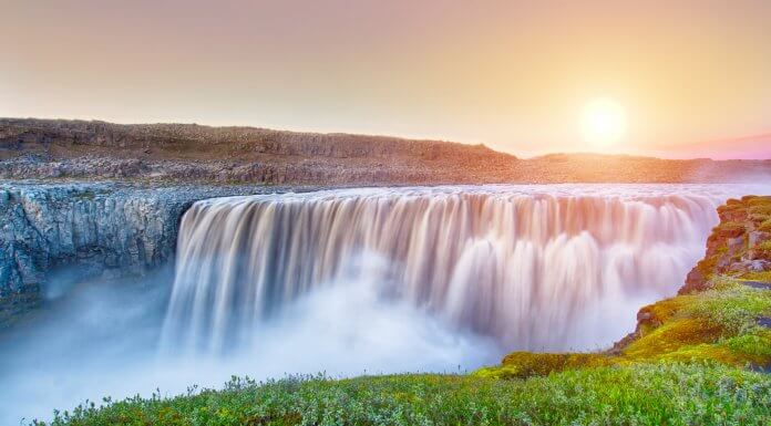 Impressive Detifoss waterfall with the midnight sun behind it.