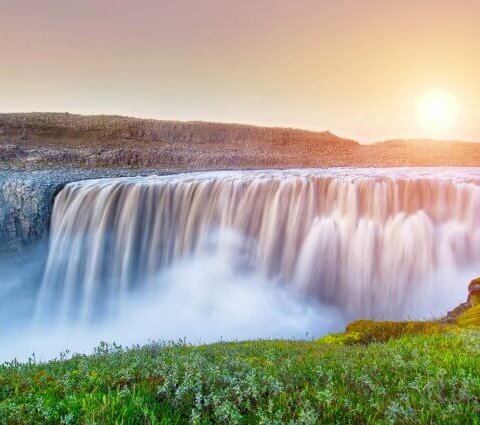 Impressive Detifoss waterfall with the midnight sun behind it.