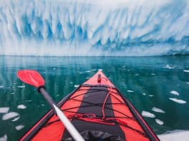 Red sea kayak facing glacier