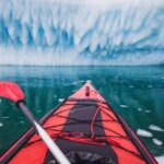 Red sea kayak facing glacier