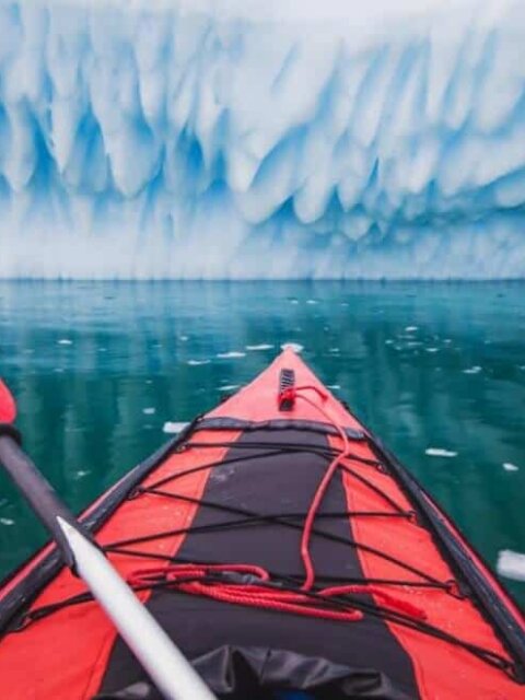Red sea kayak facing glacier