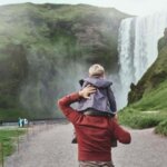 Father with son on his shoulders walking towards Skogafoss waterfall