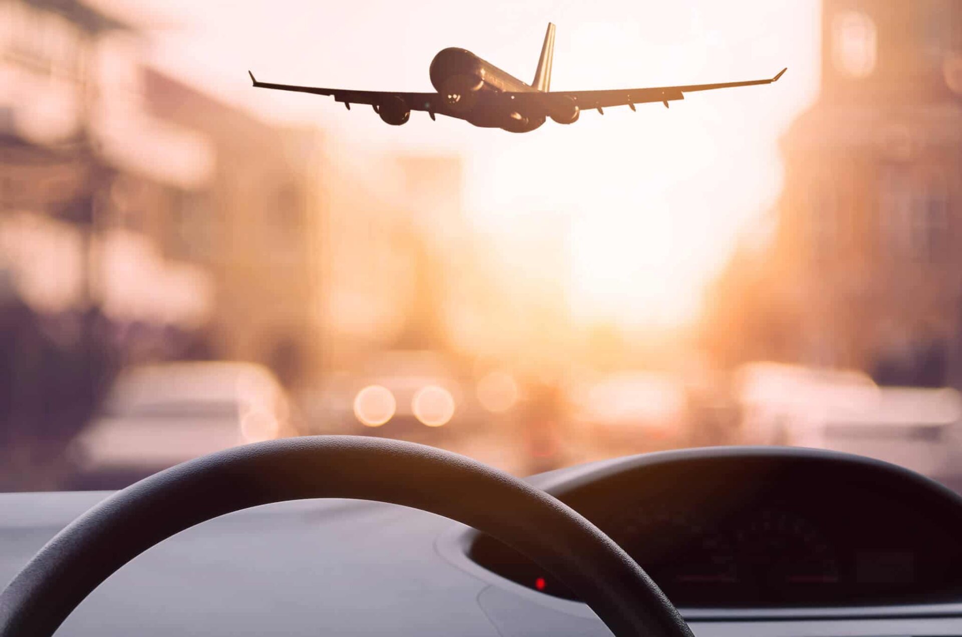 View from car dashboard of plane landing at airport