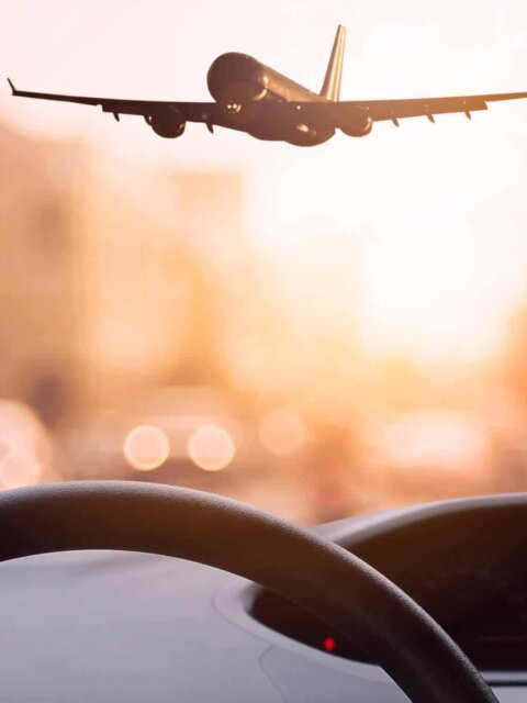 View from car dashboard of plane landing at airport
