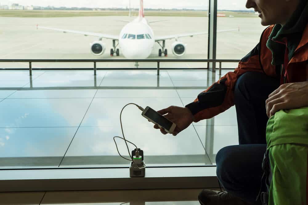 Man charging his phone with a travel adaptor, we included it in our Packing Guide For Reykjavik