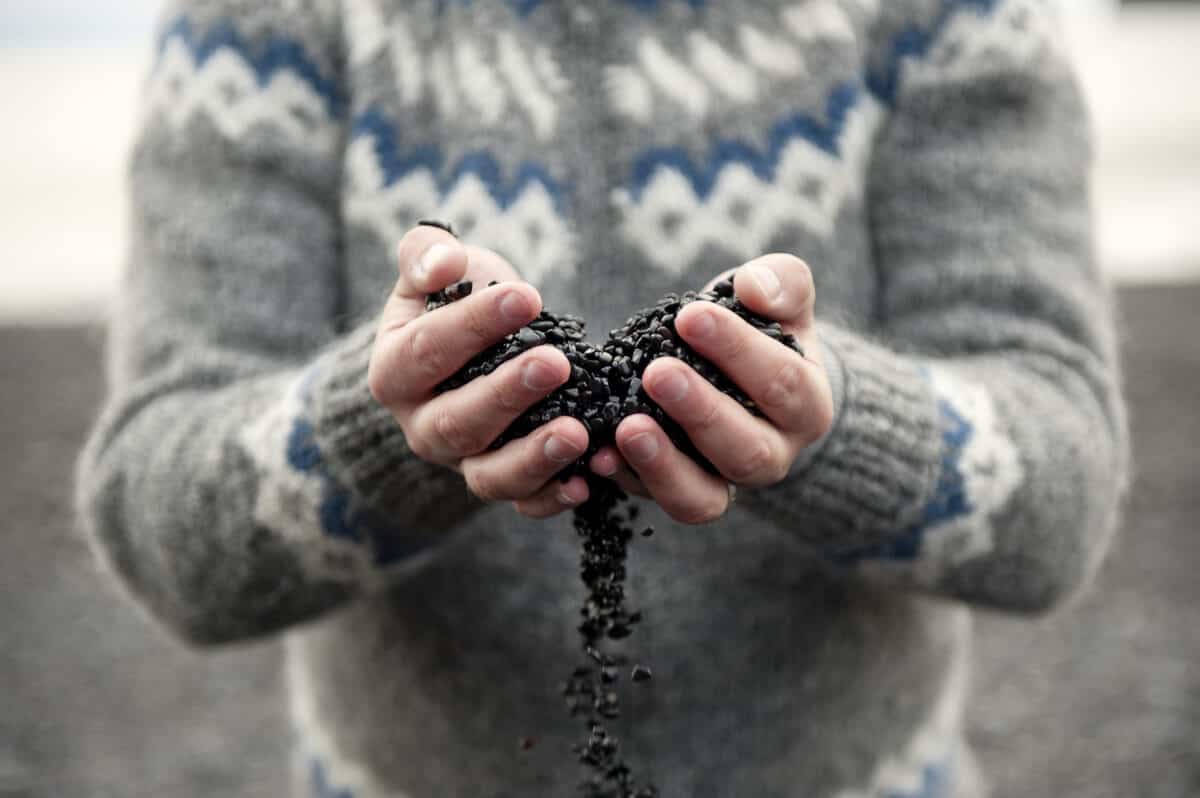 Stunning Reynisfjara Black Sand Beach in Iceland 2 Icelandic man holding black volcanic sand beach pebbles