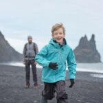 Iceland family vacation with little boy enjoying black sand beaches of Vik