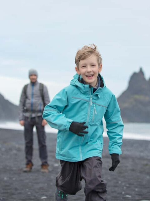 Iceland family vacation with little boy enjoying black sand beaches of Vik