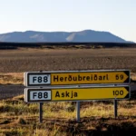 A road sign in Iceland indicating directions to Herðubreiðarl and Askja along the F88 route, with a barren landscape and distant mountains in the background.
